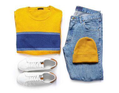 Beyaz arka planda şık kazak, kot pantolon, şapka ve ayakkabılar