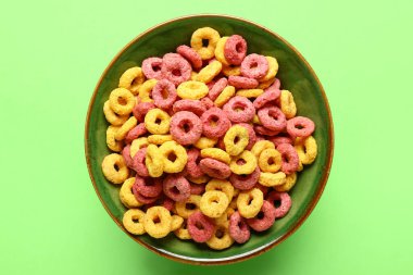 Renkli arkaplanda lezzetli mısır gevreği halkaları olan bir kase