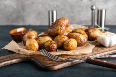 Koyu arkaplanda fırında patates ve biberiye.