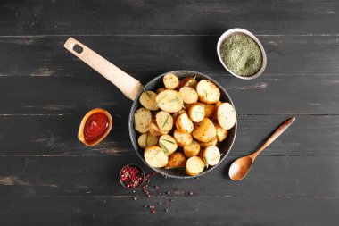 Fırında patates ve ahşap arka planda biberiye ile kızartma tavası.