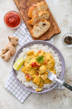 Bir kase lezzetli körili tavuk, pilav ve hafif arka planda malzemeler.