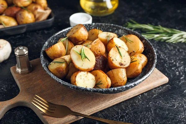 底色深色的烤土豆和迷迭香盘 — 图库照片