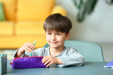 Evinde kalem kutusu olan küçük bir çocuk.