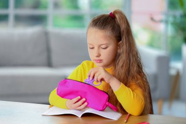 Evde kalem kutusu olan küçük bir kız.