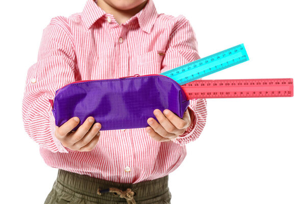 Little boy with pencil case and rulers on white background