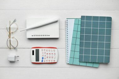 Beyaz ahşap zemin üzerinde modern Wi-Fi yönlendirici, kırtasiye ve hesap makinesi ile kompozisyon