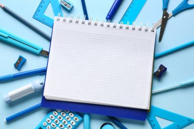 Renk arkaplanı üzerine boş defter ve kırtasiye malzemeleri