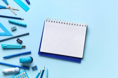 Renk arkaplanı üzerine boş defter ve kırtasiye malzemeleri