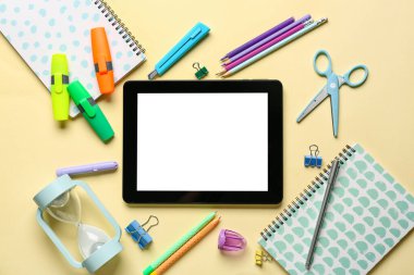 Renk arkaplanı üzerine boş tablet bilgisayarı ve kırtasiye malzemeleri