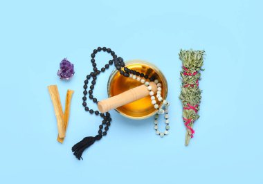 Tibet şarkı kasesi, boncuklar, otlar ve Palo Santo renkli arka planda.