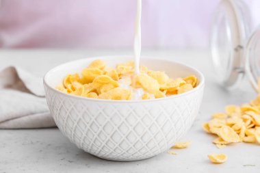 Sütü kaseye dök, masada mısır gevreği olsun, yakın plan.