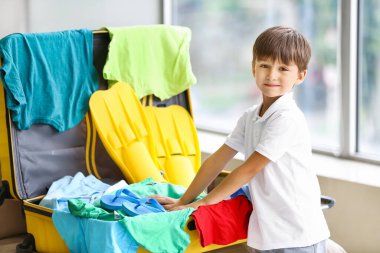 Küçük çocuk evde bavul hazırlıyor.