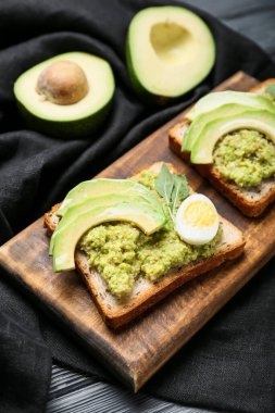 Avokado tostları ve koyu ahşap arka planda guacamole ve yumurta, yakın plan.
