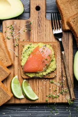 Guacamole soslu lezzetli sandviç ve ahşap arka planda somon.