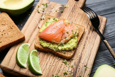 Guacamole soslu lezzetli sandviç ve koyu ahşap arka planda somon, yakın plan.