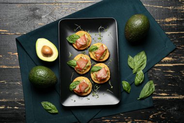 Guacamole soslu lezzetli sandviçler ve koyu ahşap arka planda jambon.