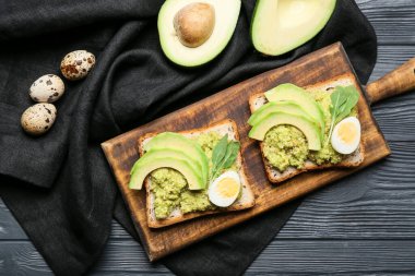 Avokado tostları, guacamole ve koyu ahşap arka planda yumurtalar.