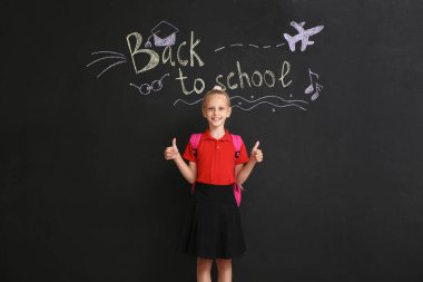 Sevimli kız karanlık arka planda okula geri dönen mesajla baş parmağını kaldırıyor.