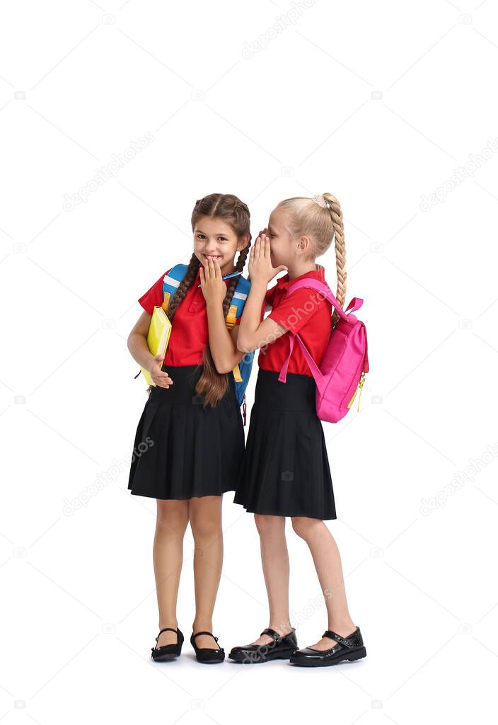Cute gossiping schoolgirls on white background