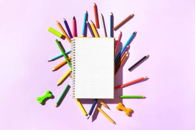 Renkli arka planda kalemleri olan defter