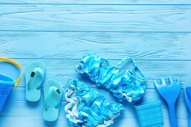 Çocuklar için plaj aksesuarları ve renkli ahşap arka planda şık bir mayo.