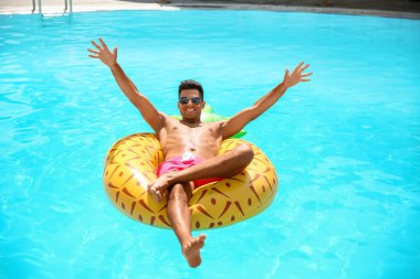 Havuzda şişme yüzüklü yakışıklı bir adam.