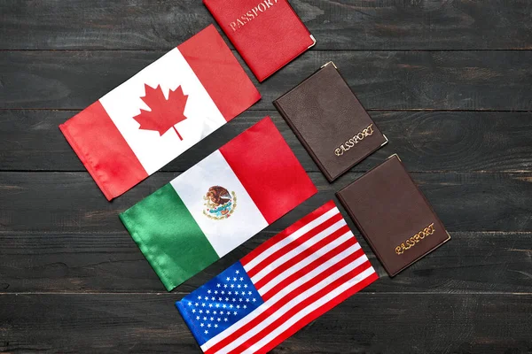 Different flags and passports on dark wooden background