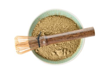 Beyaz arka planda pudralanmış kibrit çayı ve chasen ile kase