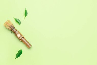 Renkli arkaplanda bambu şasen ve yeşil yapraklı kompozisyon