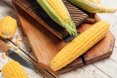 Hafif ahşap zemin üzerinde taze mısır koçanları olan tahta.