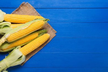 Renkli ahşap arka planda taze mısır koçanları