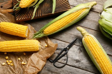Tahta zeminde taze mısır koçanları ve makas.