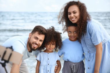 Mutlu bir aile deniz sahilinde selfie çekiyor.