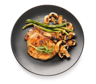 Lezzetli domuz bifteği ve beyaz arka planda ızgara sebze tabağı.