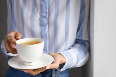 Işık duvarının yanında nefis kahve içen bir kadın, yakın plan.