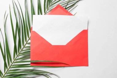 Beyaz zemin üzerinde boş kart ve palmiye yaprağı olan zarf