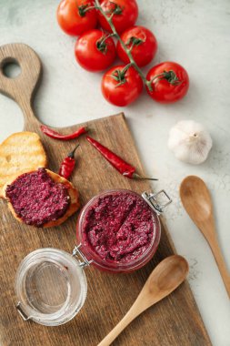 Bir kavanoz lezzetli pesto sosu ve hafif arkaplandaki malzemelerle kompozisyon.