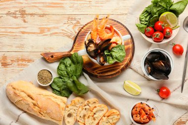 Lezzetli Cacciucco çorbası ve hafif ahşap arka planda malzemeler.