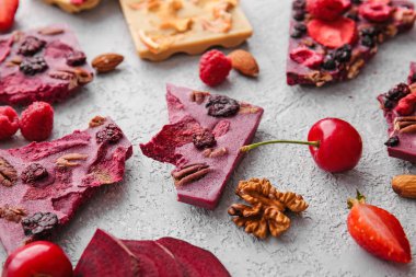 Gri arka planda meyveli, meyveli ve fındıklı el yapımı çikolatalar.