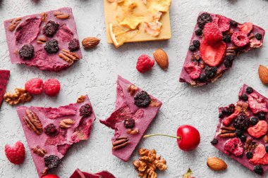 Gri arka planda meyveli, meyveli ve fındıklı el yapımı çikolatalar.