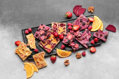 Gri arka planda meyveli, meyveli ve fındıklı el yapımı çikolatalar.