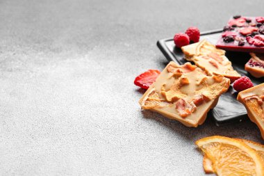 Gri arka planda meyveli, meyveli ve fındıklı el yapımı çikolatalar.