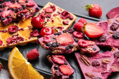 Gri arka planda meyveli, meyveli ve fındıklı el yapımı çikolatalar.