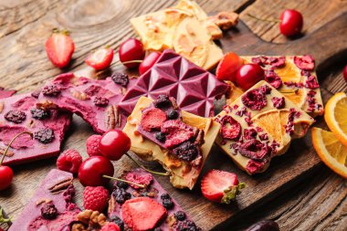 Ahşap zemin üzerinde meyve ve böğürtlen bulunan el yapımı çikolatalar.