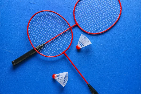Badminton rackets and shuttlecocks on color background
