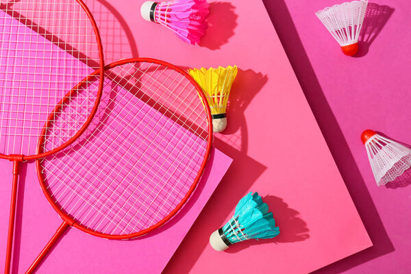 Badminton rackets and shuttlecocks on color background