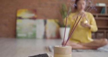Tibet şarkı kasesiyle meditasyon yapan genç bir kadının odasında tütsü yakmak.
