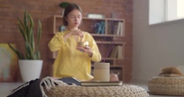 Tibet şarkı kasesiyle meditasyon yapan genç bir kadının odasında tütsü yakmak.