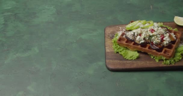 新鮮なワッフルに野菜とチーズを背景色にレモンを絞るシェフ — ストック動画