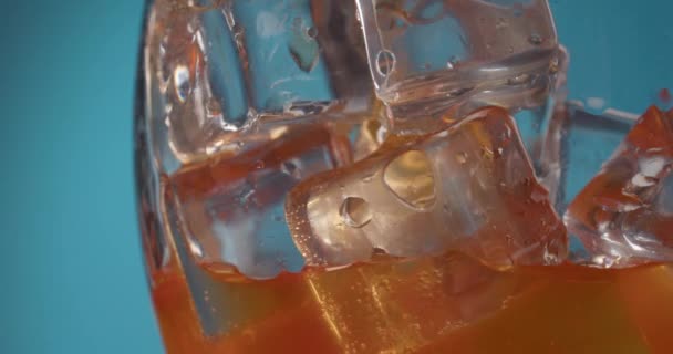 Gießen Von Aperol Glas Mit Eis Auf Farbigem Hintergrund Nahaufnahme — Stockvideo